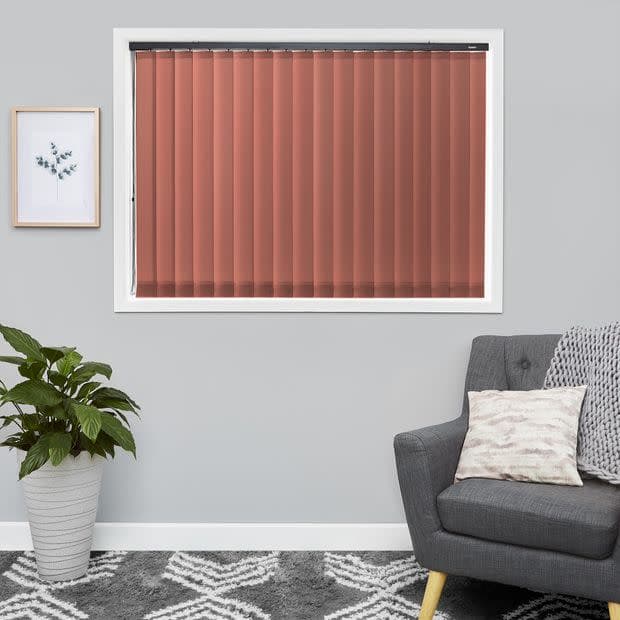 Vertical terracotta blinds, fully closed and filtering light through slats; in a white-framed window of a grey-walled living room with a grey armchair, potted plant and framed print.