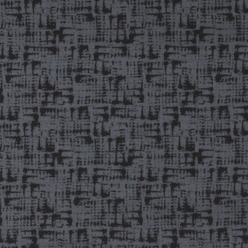 Patterned dark-gray carpet with irregular black crosshatch texture — covering a flat floor surface — in a dimly lit indoor setting, appearing uniform and tightly woven.