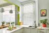 White horizontal blinds covering a tall kitchen window, closed and slightly tilted to filter sunlight and cast striped shadows; modern, bright kitchen with marble countertops, sink, pendant lights, and plants.
Text found: PANTONE