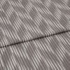 Folded curtain fabric sample with narrow, irregular vertical grey and off-white stripes; folded edge across center, shown close-up on a neutral surface under soft, diffuse lighting.