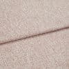 Pink-speckled upholstery fabric with a fine bouclé texture, folded and layered along a horizontal crease; lying flat in a close-up view with soft, even lighting.