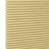 Honeycomb cellular blind, beige with visible hexagonal cells at left edge and narrow horizontal pleats — fully lowered and closed, filtering soft light in a close-up, neutral setting.