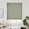 Sage-green pleated blind, fully lowered over a window with visible lower sash, filtering daylight; above a dining table with glassware, vase of daisies, framed art and a fiddle‑leaf fig.