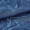 Dark navy jacquard fabric with raised, tufted wavy pattern folded over itself, revealing woodgrain-like texture; close-up studio shot with soft lighting accentuating sheen and depth.