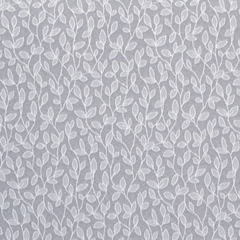Sheer, white-embroidered curtain hung flat, its repeating vine-and-leaf motif running vertically; filtering soft light against a muted gray background, suggesting an interior window or decorative wall covering.