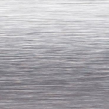 Brushed stainless-steel surface with fine horizontal grain; reflecting diffuse light and subtle highlights, close-up view suggesting a sheet-metal or appliance panel in a neutral, evenly lit studio context.