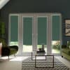 Glass double doors with teal-green roller blinds covering the panes; blinds partially lowered; modern living room context with olive armchairs, glass coffee table, chevron rug and a garden beyond.