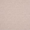 Textured pink-beige wallpaper, densely speckled with fine reddish dots, covering a flat wall and creating a subtle woven appearance in soft, even indoor lighting.