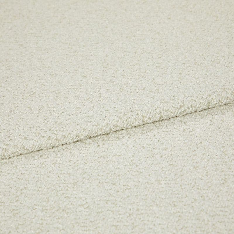 Cream bouclé fabric folded into overlapping layers, showing a horizontal seam; close-up view with soft, even lighting emphasizing the looped texture in a neutral studio setting.
