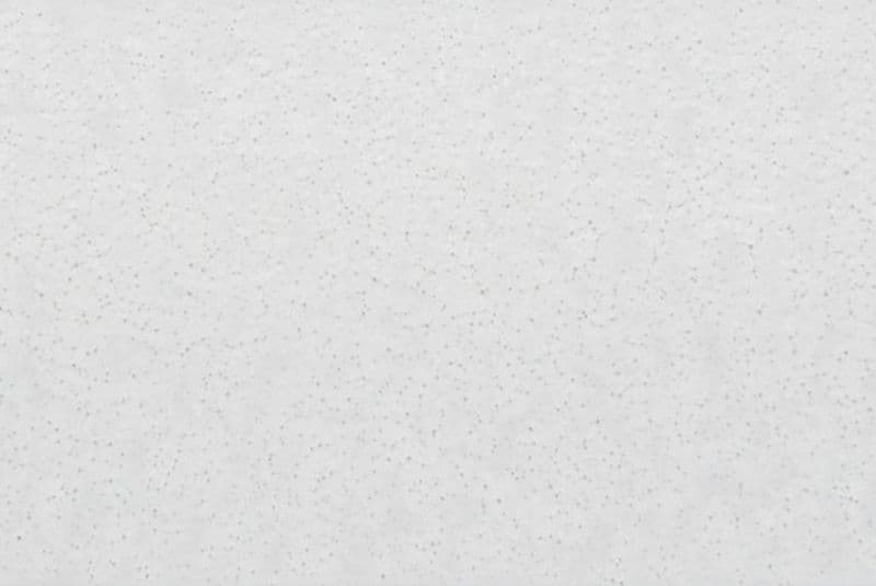 White acoustic ceiling tile with small gray speckles, mounted flush overhead, forming a continuous textured ceiling surface in a softly lit interior with even diffuse lighting and no visible fixtures.