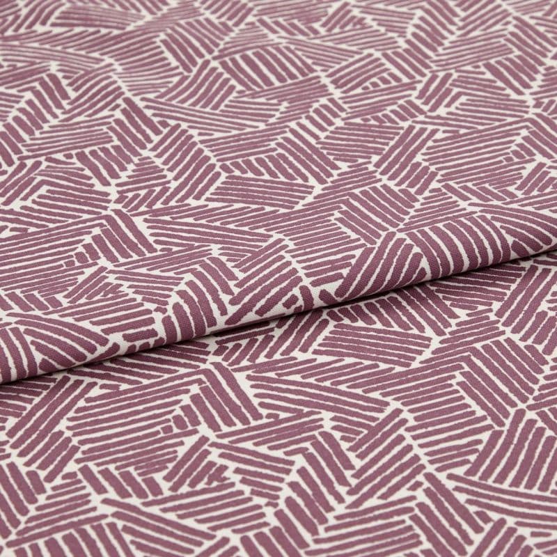 Folded printed cotton fabric with mauve geometric stripe blocks, repeating irregular parallelograms; folded edge runs diagonally, fabric lies flat under soft studio lighting for a close-up textile view.