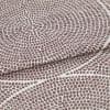 Brown-dot jacquard fabric, folded once with overlapping edge; dots form concentric circular patterns, slightly raised texture, photographed in close-up under neutral studio lighting on a pale background.