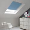 Room with white eaves wall, dark blue-grey wall to right with a shabby chic white drawer unit, a contemporary white chair, white painted floorboards and a skylight blind in pale sea blue.