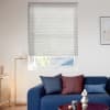 White cellular pleated blind lowered across window, translucent and filtering soft daylight; small modern living room with blue sofa, textured cushions, brass floor lamp, coffee table and framed abstract art.
