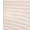 Cellular (honeycomb) pleated blind, cream-colored, fully lowered and closed with visible hexagonal cells; diffusing soft light across a plain interior wall, suggesting a bright, neutral room.
