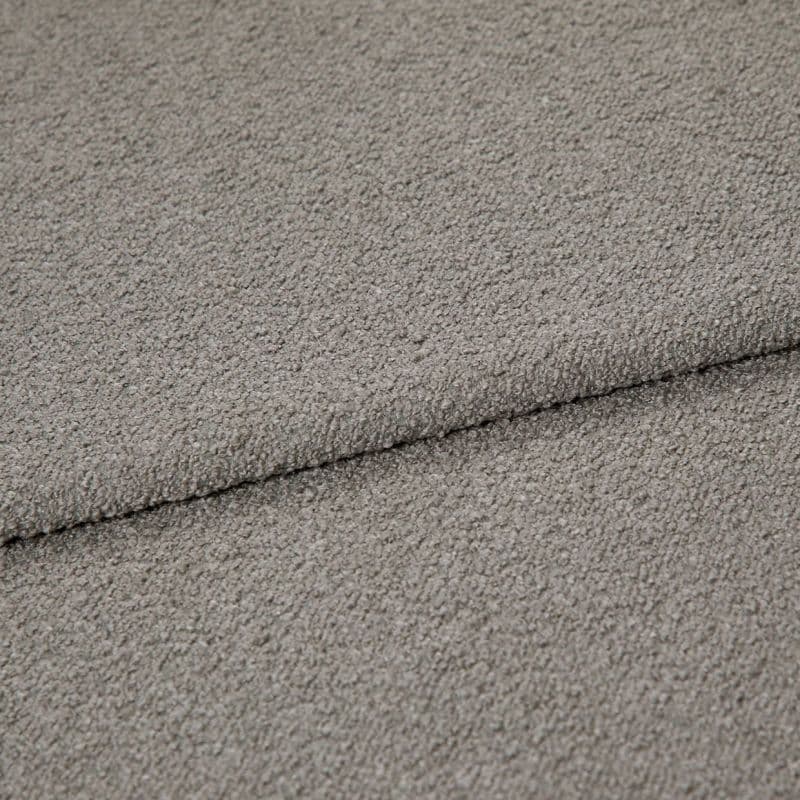 Gray boucle upholstery fabric folded to show an overlapping edge; dense looped texture; close-up, evenly lit studio view of a neutral-colored textile surface.