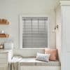 Grey horizontal blinds with vertical ladder tapes covering the window, closed and filtering soft daylight; cozy kitchen nook with built-in cushioned bench, pillows, wall sconce, countertop and bread tin.
BREAD