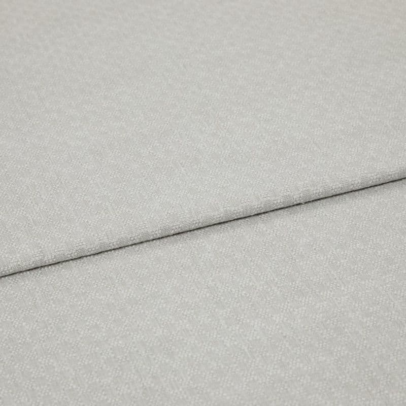 Light grey textured fabric panels overlapping slightly; top panel folded along a seam. Close-up view emphasizing woven pebble pattern, soft matte lighting, minimal background, studio-like neutral setting.