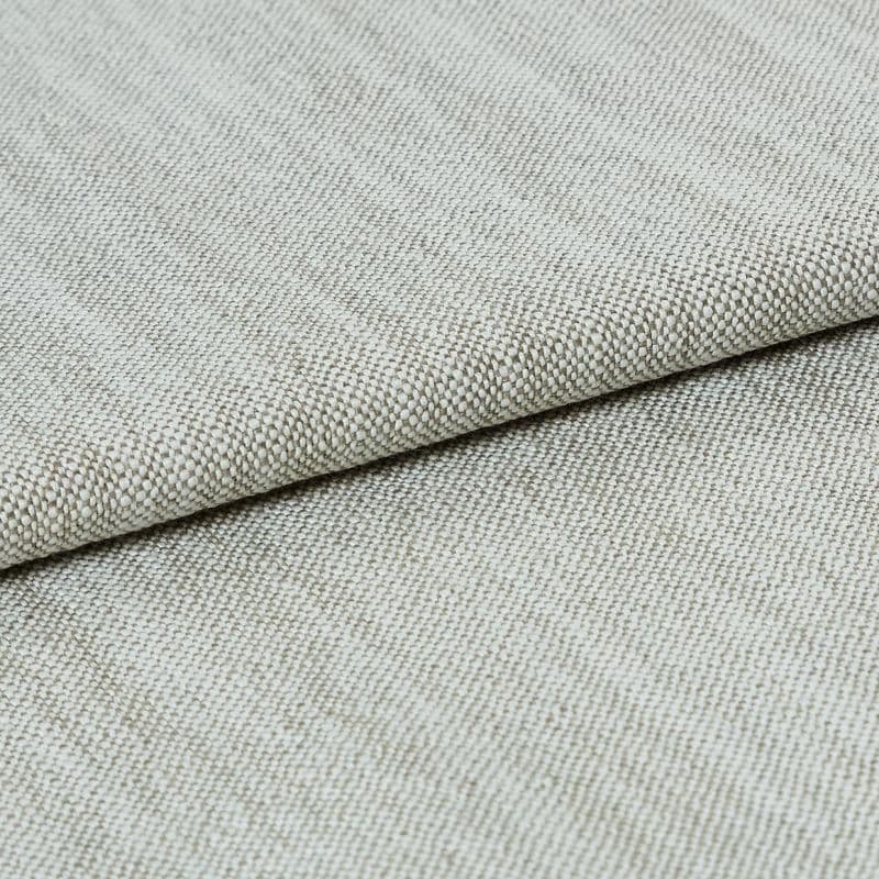 A beige, tightly woven upholstery fabric folded once, revealing a textured basket-weave edge; lying flat on a neutral surface under soft, even studio lighting.