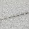Light-gray, pebble-patterned upholstery fabric folded once, textured with a subtle metallic sheen; close-up view on a neutral surface under soft, diffuse lighting.