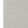 White pleated honeycomb (cellular) blind, fully lowered with visible hexagonal cells at left edge, closed and softly filtering light, close-up interior view with neutral lighting.