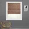 Roman shade with gray fabric and orange geometric lattice, lowered over a white window with its bottom raised, filtering daylight; gray wall, gold wire chair left, abstract print right.