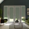 Glass French doors covered by patterned roller blinds that block most light, revealing a garden strip below; modern living room surrounds with green armchairs and a glass coffee table on a chevron rug.