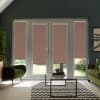 Patio doors with four rose-beige roller blinds lowered partially, in a living room with green chairs, glass coffee table on a chevron rug and a glimpse of the garden outside.