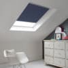 Room with white eaves wall, dark blue-grey wall to right with a shabby chic white drawer unit, a contemporary white chair, white painted floorboards and a skylight blind in oxford blue.