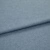 Light blue woven fabric (denim-like) folded once, forming a diagonal layered edge; close-up view showing fine texture and even studio lighting on a plain surface.