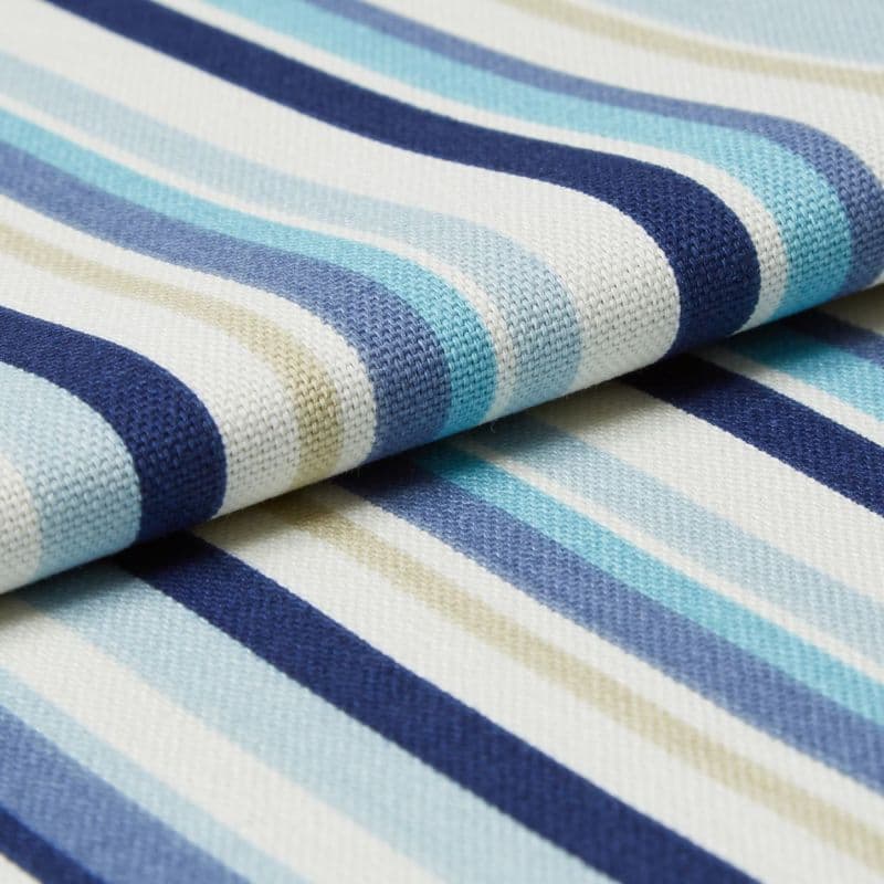 Folded woven fabric swatch with alternating navy, light-blue, teal and beige stripes on white; tightly knit texture. Folded overlap creates layered bands in a close-up, softly lit studio setting.
