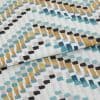 Fabric with abstract rectangular brushstroke pattern (teal, mustard, black, gray) — folded across the frame — close-up studio shot showing textured cotton/linen surface and even soft lighting.