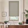 Roller blind covers window, partially lowered to filter light; stainless faucet and sink sit below on marble countertop amid bowls of leafy greens, potted plants, and framed sketch.