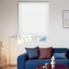 White cellular blind lowered over a rectangular window, covering most glass with subtle horizontal pleats and filtering daylight; bright minimalist living room with blue sofa, floor lamp and framed art.