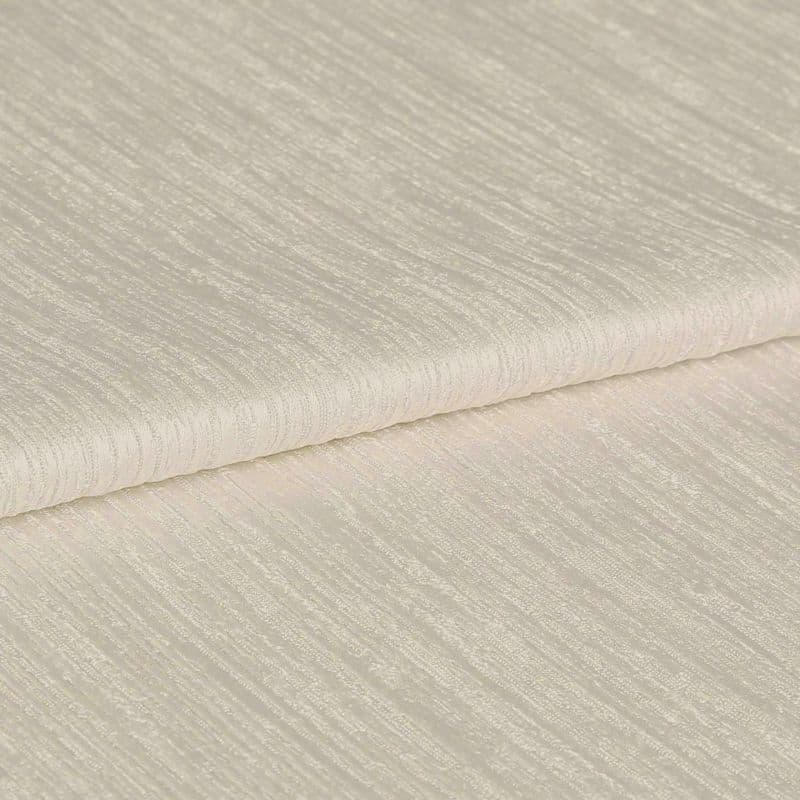 Folded cream, ribbed curtain fabric sample; tightly folded edge across the center, showing subtle horizontal textured stripes; close-up on a flat surface under soft, even studio lighting.