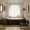 White pleated cellular blind fully lowered over window, softly diffusing daylight; a built-in bathtub beneath with dark wood paneling, vessel sink, striped beige walls, wooden floor, minimal shelf.