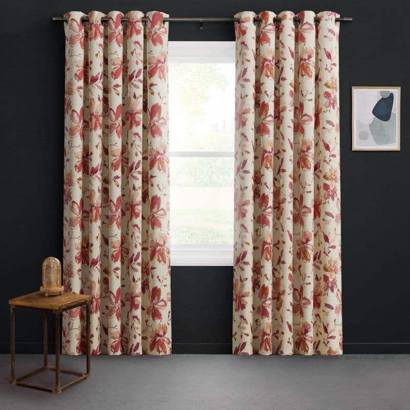 Floral-patterned grommet curtains, cream with red-pink blossoms, hung on a metal rod and drawn slightly apart; filtering daylight through a central double-hung window in a dark-walled modern room.