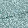 Woven teal upholstery fabric with irregular white abstract print; folded along a seam, lying flat; close-up studio view showing texture and weave.
