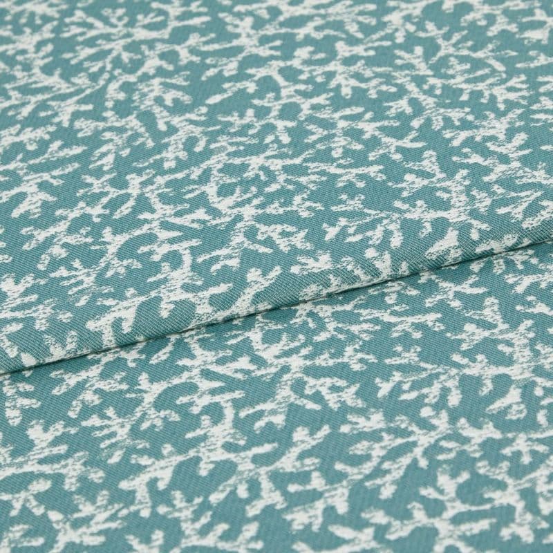 Woven teal upholstery fabric with irregular white abstract print; folded along a seam, lying flat; close-up studio view showing texture and weave.