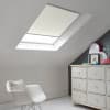 Room with white eaves wall, dark blue-grey wall to right with a shabby chic white drawer unit, a contemporary white chair, white painted floorboards and a skylight blind in pale cream.