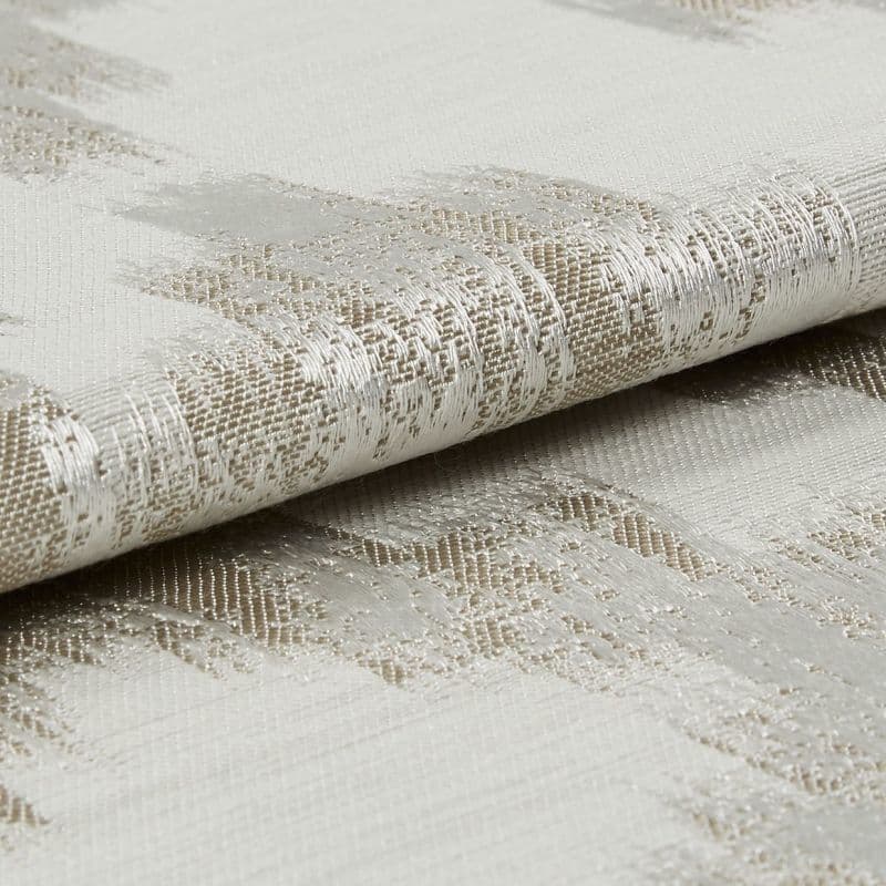 Woven curtain fabric, folded to reveal a metallic-thread abstract pattern and textured weave, reflecting light; close-up, neutral studio lighting.