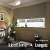 Grey fabric Roman blind, lowered about three-quarters with a neat hem, filtering soft daylight. Cozy neutral living room with tall snake plant, side tables, candle, radiator, tiled roof and distant treeline.
AS SEEN IN
Ideal Home &
Livingetc