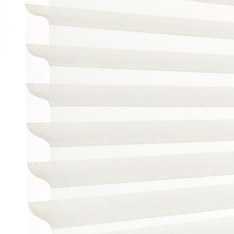 White horizontal pleated cellular blind with scalloped edges, fully lowered and closed, filtering bright daylight; close-up view showing soft shadowed ridges against a pale background.