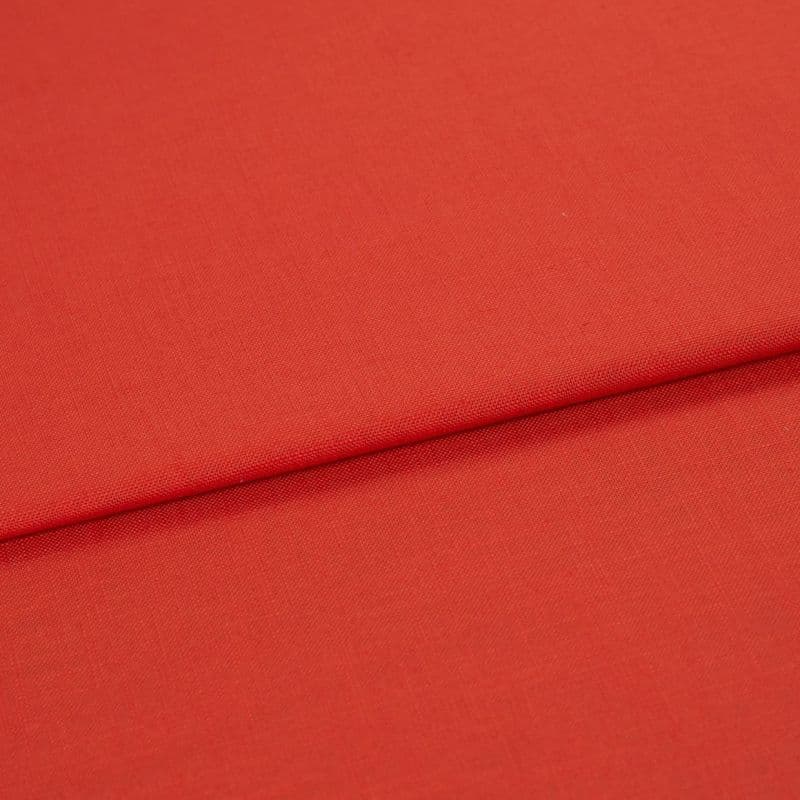 Red woven fabric panel with visible fine texture, folded across the frame forming a horizontal overlap; lying flat under soft, even studio lighting with no other objects or background details.