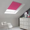 Room with white eaves wall, dark blue-grey wall to right with a shabby chic white drawer unit, a contemporary white chair, white painted floorboards and a skylight blind in hot pink.