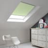 Room with white eaves wall, dark blue-grey wall to right with a shabby chic white drawer unit, a contemporary white chair, white painted floorboards and a skylight blind in pale sea green.