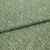 Folded green boucle upholstery fabric with white flecks, layered one fold over another; resting flat and revealing textured weave, photographed close-up under soft neutral studio lighting.