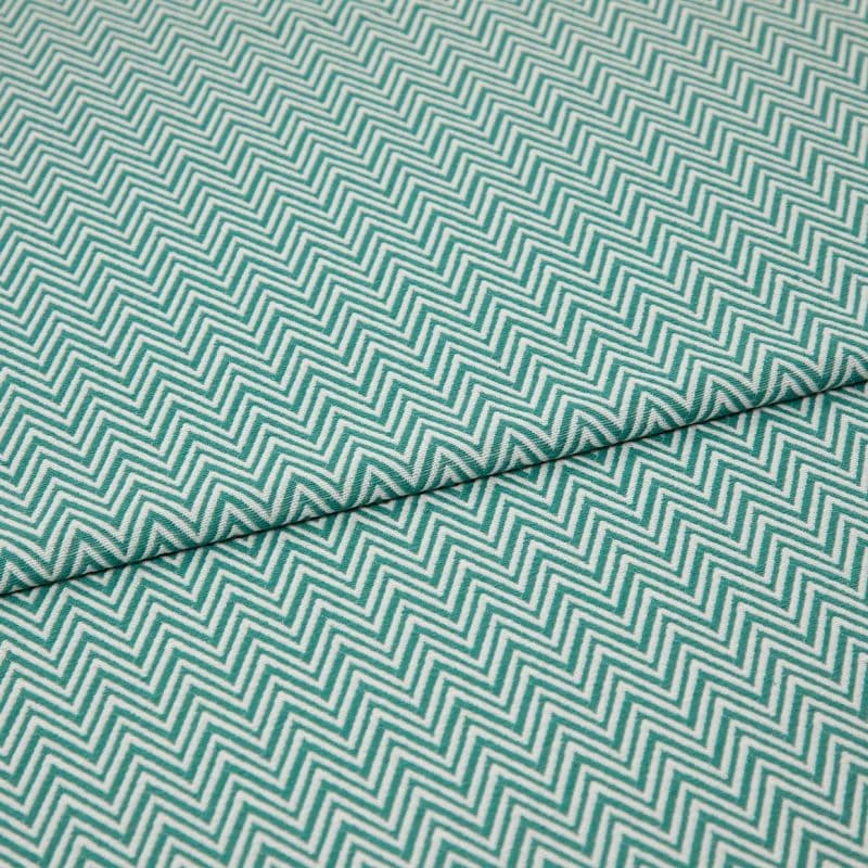 Folded teal-and-white chevron fabric (zigzag pattern) — folded once forming a horizontal seam — close-up, evenly lit textile filling the frame, showing texture and repeating geometric pattern.
