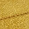 golden-yellow textured upholstery fabric folded diagonally, overlapping seam visible; short plush pile creates a mottled sheen, presented in a tight close-up under soft, even studio lighting.