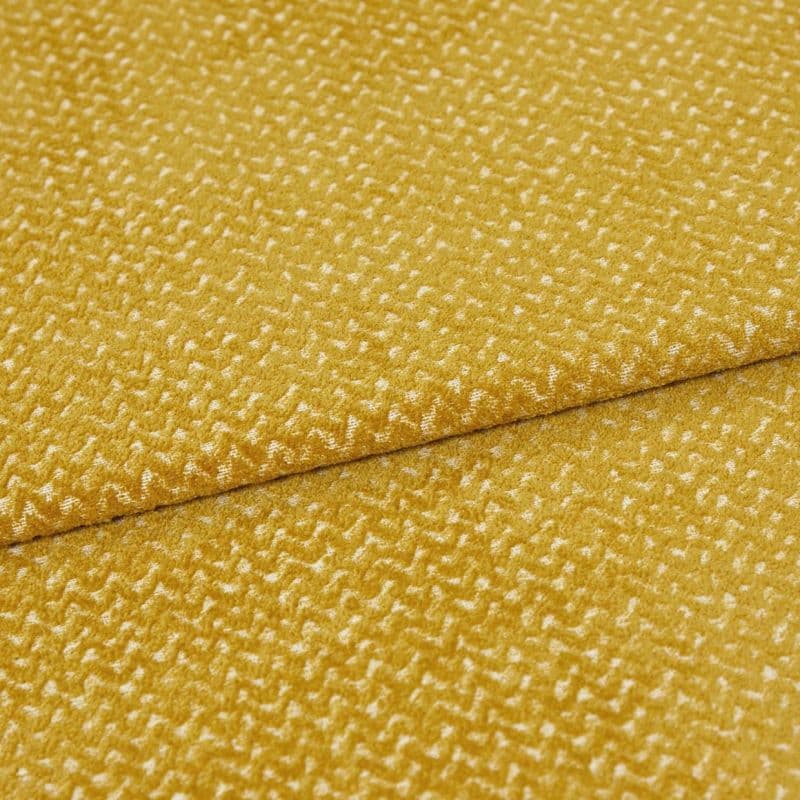 golden-yellow textured upholstery fabric folded diagonally, overlapping seam visible; short plush pile creates a mottled sheen, presented in a tight close-up under soft, even studio lighting.